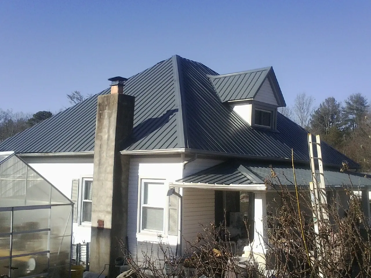 Dark blue standing seam metal roof on a white farmhouse with dormer — Slate & Tile Roof Repair by Roofing Brothers in Aldie