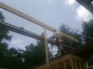 Carpenter setting a ridge beam over a new addition frame — Ice Dam Removal by Roofing Brothers in Aldie