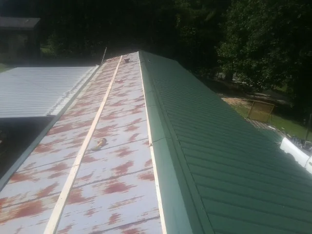 Old rusted panels beside newly installed green metal roofing — Wind Damage Roof Repair by Roofing Brothers in Aldie