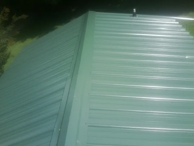 New green metal panels meeting at the ridge of a roof — Flat Roof Repair work by our crew in Aldie