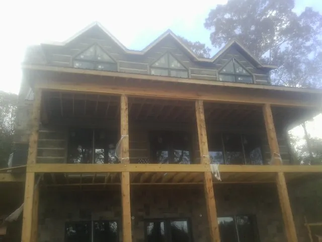 Dormers and porch framing on a large log home under construction — Roof Coating work by our crew in Aldie