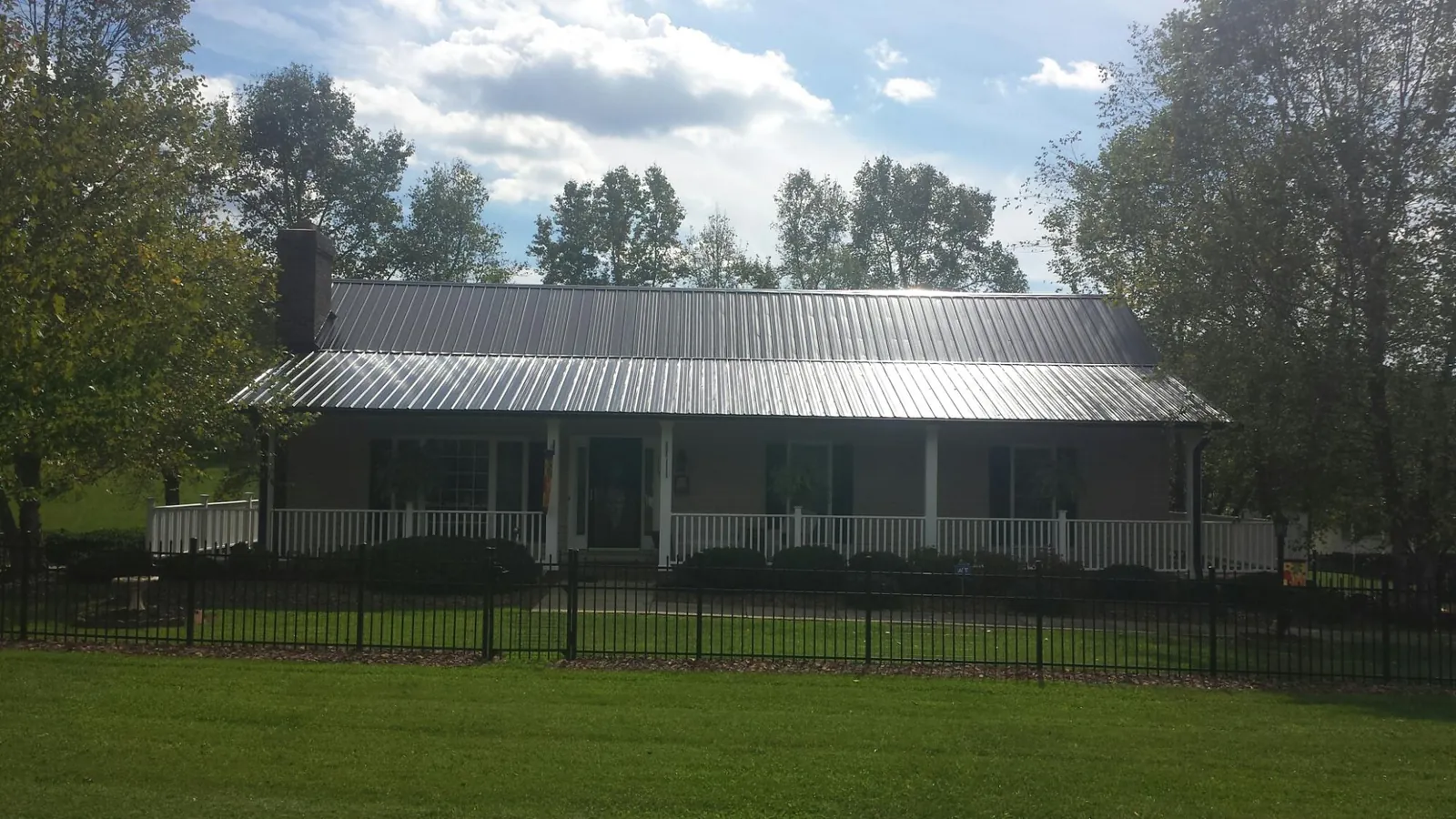 Gray metal roof on a brick ranch with a full width front porch — Gutter Guard Installation work by our crew in Aldie