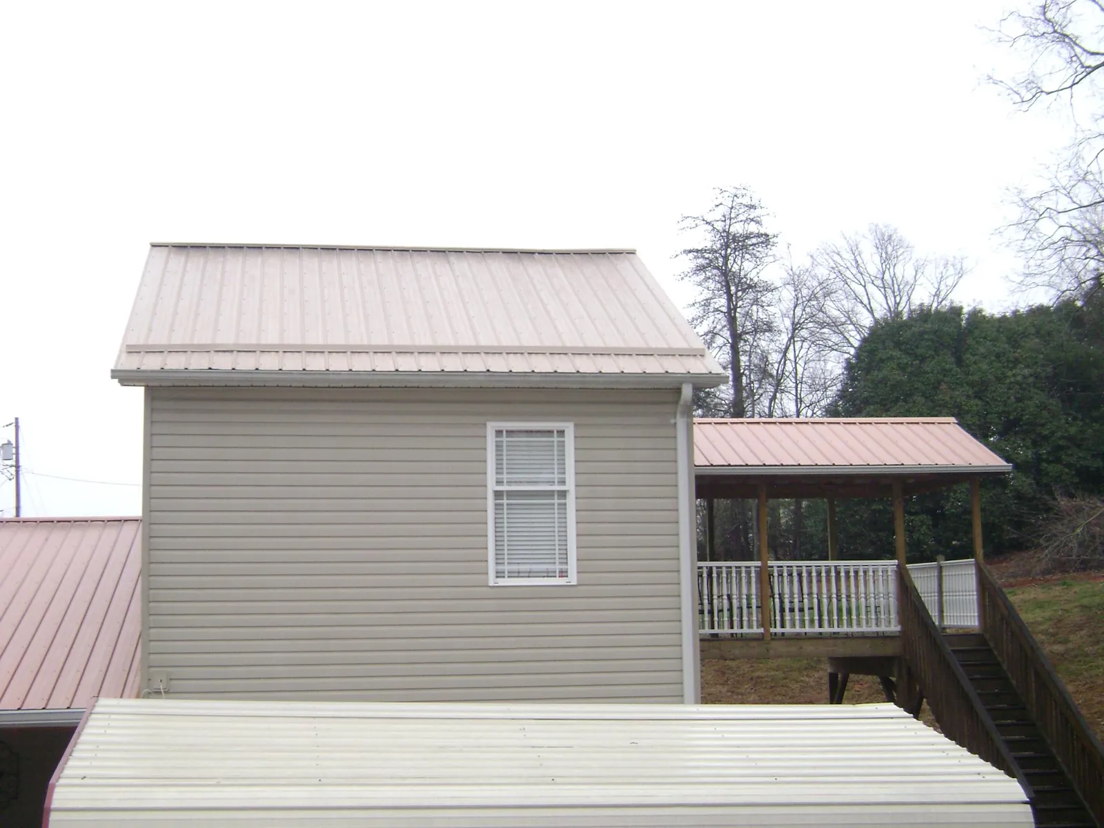 Tan metal roofs on a two story addition and attached porch, from a Roof Replacement job in Aldie