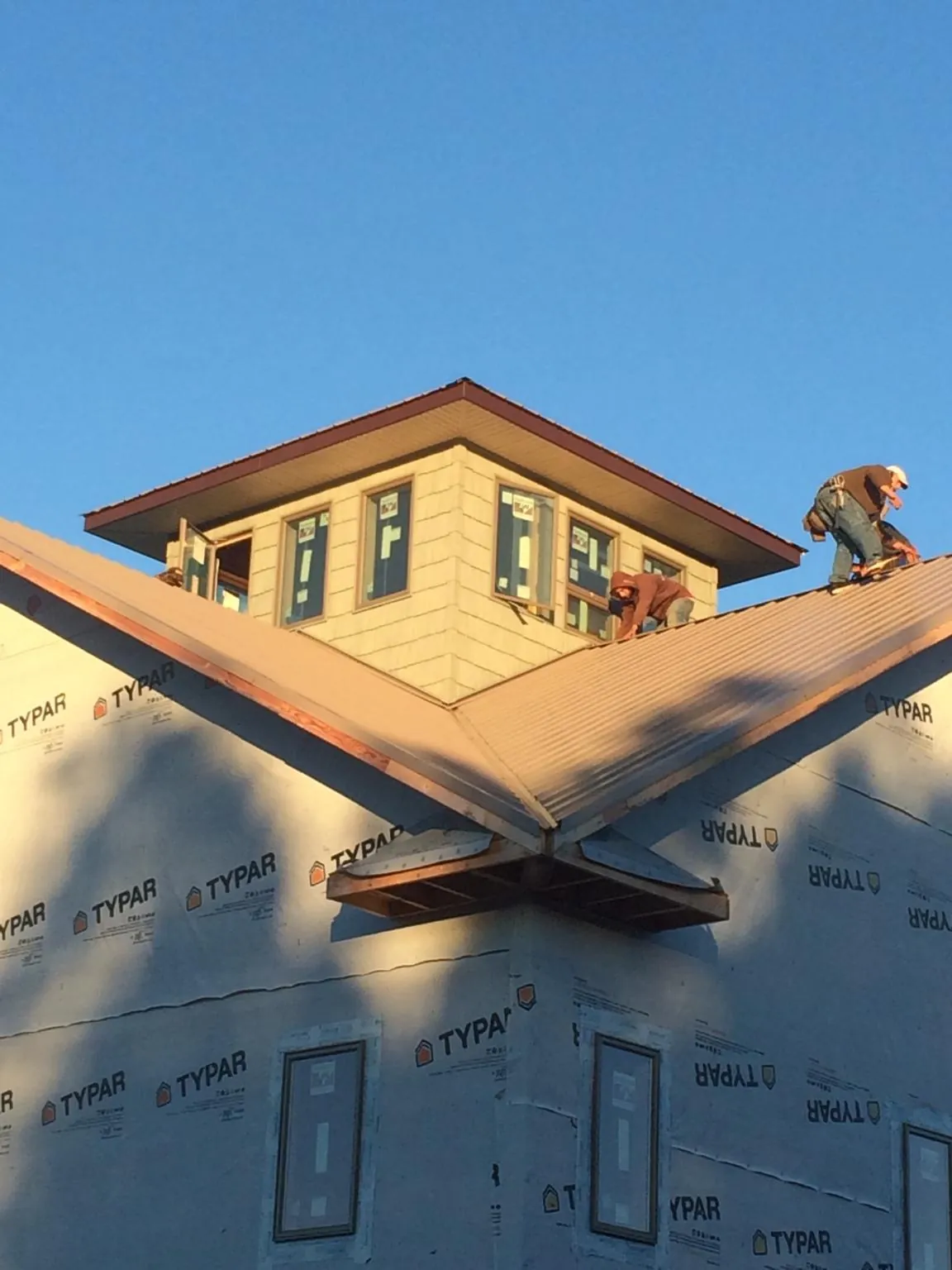 Roofers working around a rooftop cupola on a new metal roof at sunset — Roof Waterproofing in Aldie by Roofing Brothers